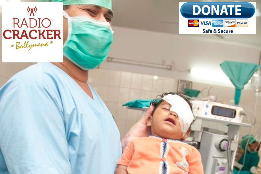 Indian medical assistant holding a child after a cataract operation